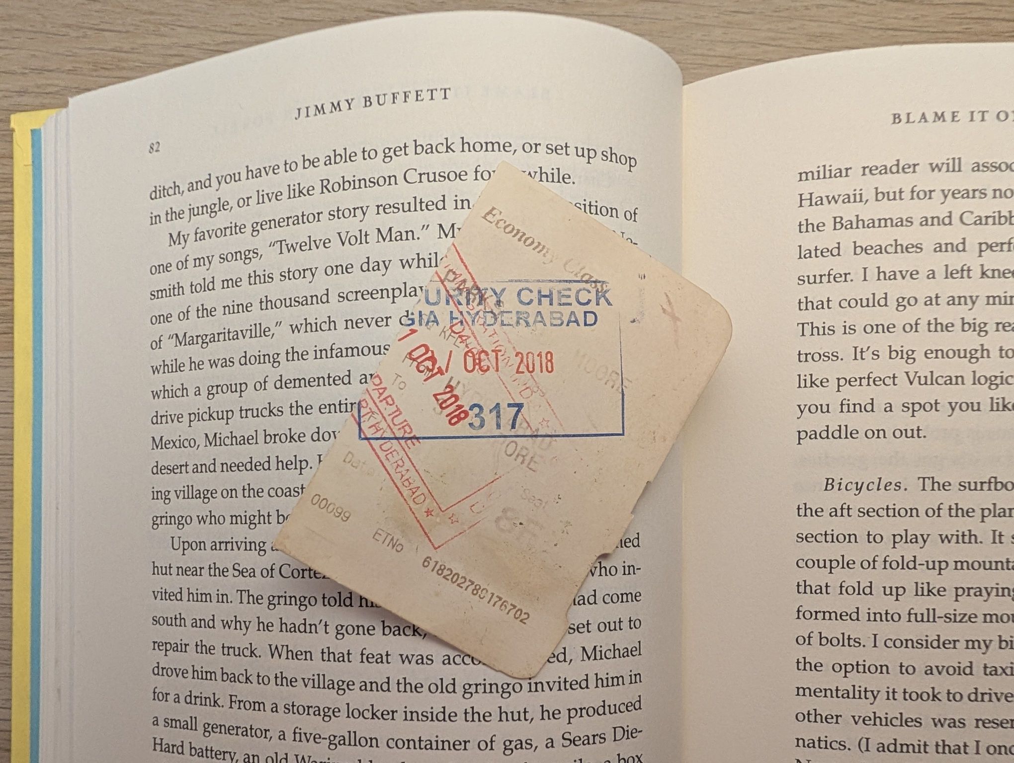 An image of the book A Pirate Looks at Fifty by Jimmy Buffett, open to a page with a stamped boarding-pass stub to Hyderabad sitting atop the open page